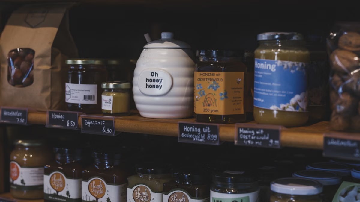 Explore artisanal honey jars and local products neatly displayed on wooden shelves in a charming Dutch shop.